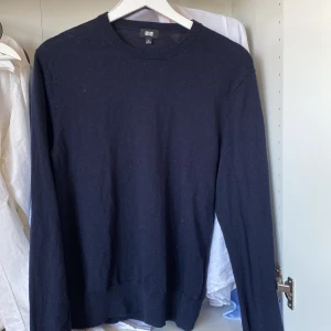 Mörkblå tröja från Uniqlo - Säljer en stilren svart tröja från Uniqlo. Tröjan har en klassisk design med rund hals och långa ärmar. Perfekt för en minimalistisk look.