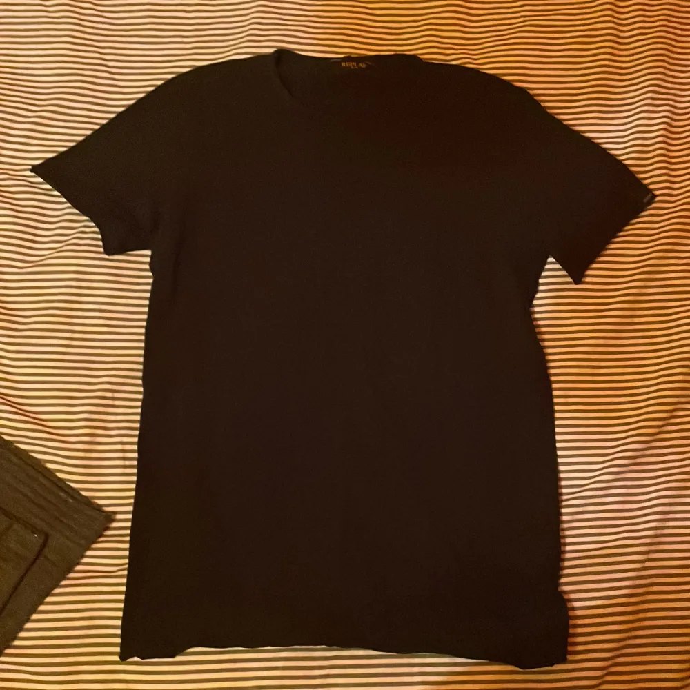 Säljer en stilren svart t-shirt från Replay. Den har en klassisk design med korta ärmar och rund hals. Perfekt för en enkel och snygg look.. T-paidat.
