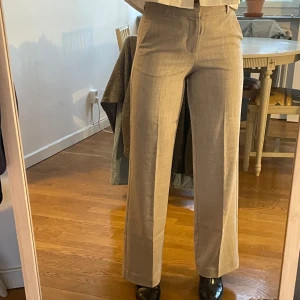 Begie kostymbyxor  - Snygga beige kostymbyxor med hög midja och en klassisk rak passform. Perfekta för en stilren look.