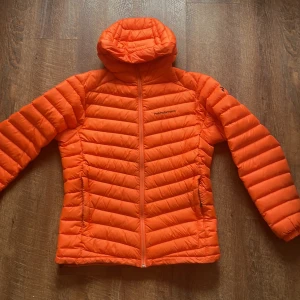 Peak Performance Jacka - Säljer en snygg orange dunjacka från Peak Performance. Perfekt för kyliga dagar med sin långa ärmar och bekväma passform. Jackan är använd ett fåtal gånger. Jackan är nästintill nyskick, strl M. Bara höra av er vid frågor! 
