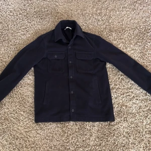 Marinblå overshirt från Zara - Snygg mörkblå overshirt från Zara med knappar framtill och två bröstfickor med lock. Perfekt till våren. Använd några enstaka gången
