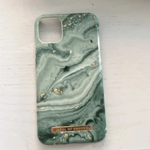 Grönt marmorerat mobilskal från iDeal of Sweden IPhone 11 - Snyggt mobilskal med marmorerat mönster i grönt och inslag av guld. Skalet har en elegant design och är perfekt för att ge din telefon ett stilrent utseende. Märket iDeal of Sweden står för kvalitet och trendig design. iPhone 11. Ny pris=249 kr
