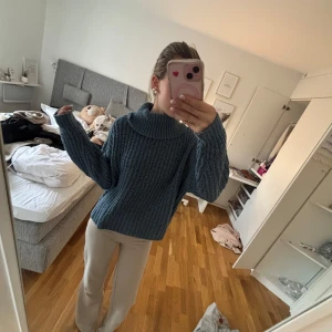 Blå stickad polotröja - Säljer en mysig blå stickad polotröja med en bred krage. Perfekt för kyliga dagar och ger en avslappnad stil. Tröjan har långa ärmar och en lös passform. 