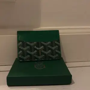 Snyggt och stilrent grönt kortfodral med deras ikoniska mönster. Perfekt för att hålla dina kort organiserade och lättillgängliga. En lyxig accessoar för den modeintresserade.