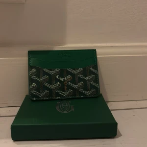 Grön korthållare - Snyggt och stilrent grönt kortfodral med deras ikoniska mönster. Perfekt för att hålla dina kort organiserade och lättillgängliga. En lyxig accessoar för den modeintresserade.