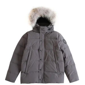 Grå dunjacka från Canada Goose - Säljer en stilren grå dunjacka från Canada Goose med en avtagbar huva kantad med päls. Jackan har en broderad logotyp på ärmen och stängs med dragkedja och knappar. Perfekt för kalla vinterdagar.