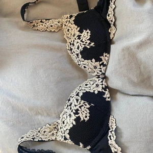 Svart spets-bh med blommigt mönster - Elegant svart bh med vacker blommig spetsdetalj i beige. Perfekt för att känna sig extra fin under kläderna. Justerbara axelband för bästa passform.