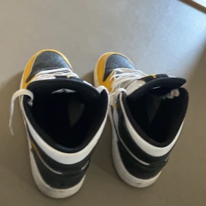 Nike Air Jordans i svart, vit och gul - Snygga Nike Air Jordans i en fräsch kombination av svart, vit och gul. Skorna har klassisk snörning och den ikoniska Air-loggan på plösen. Perfekta för dig som vill ha en stilren och sportig look. 