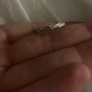 Två silverringar med blommönster - Säljer två vackra silverringar. Den ena har ett elegant blommönster med små detaljer, medan den andra har ett mer subtilt, ingraverat mönster. Perfekta för att ge en stilfull touch till din look.