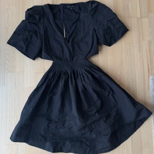 Svart klänning med v-ringning - Snygg svart klänning från Banana republic med v-ringad hals och korta ärmar. Den har en elastisk midja som ger en fin passform och en lätt utställd kjol. Perfekt för en stilren look.