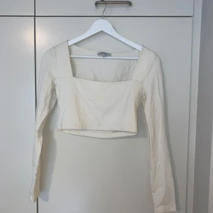 Långärmad crop top - En vit långärmad crop top från Chiquelle, i storlek S. Den har fyrkantig urringning och har tight passform. Använd ett antal gånger men fortfarande i väldigt bra skick. Materialet är relativt tjockt och av kvalité.