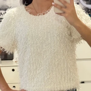 Söt vit topp - Säljer en vit kortärmad topp från Kappahl med fluffig och glittrig yta som ger en unik look. Använd es endast en gång då den är för liten.