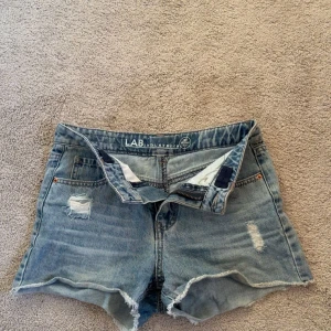 Blå jeansshorts  - Snygga blå jeansshorts med fransig kant och slitna detaljer framtill. Klassisk femficksmodell med knapp och dragkedja. Perfekt för dig som gillar en chill och avslappnad stil❣️