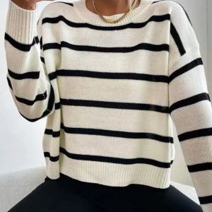 Vit och svart randig stickad tröja - Säljer en snygg stickad tröja med breda svarta ränder på vit botten. Tröjan har rund hals, långa ärmar och en loose passform som ger en chill vibe. Perfekt att matcha med jeans eller svarta byxor för en enkel men stilren look.