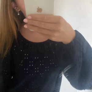 Mörkblå blus med broderade detaljer - Säljer en mörkblå blus från Vila i storlek XS. Blusen har broderade hålmönster över hela tyget, rundad hals och långa puffiga ärmar med resår vid ärmslut. Baksidan har en liten öppning upptill. Använd ungefär 2 gånger!!