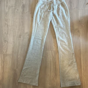 Grå mjukisbyxor med bootcut - Säljer ett par ljusgrå mjukisbyxor med bootcut och snörning i midjan. Byxorna har en bekväm resår i midjan och är tillverkade i mjukt bomullsmaterial. Perfekta för chill dagar eller när du vill vara extra bekväm.