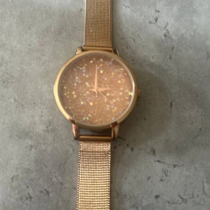Glittrig rose klocka med mesharmband - Snygg klocka i rosé färg med glittrig urtavla som reflekterar ljuset i olika färger. Rund boett och stilrent mesharmband i metall ger en modern vibe. Perfekt accessoar för dig som gillar att sticka ut med detaljer som glittrar. (Inget batteri!!)