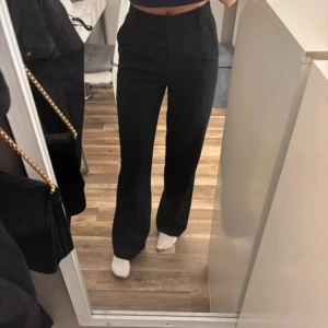 Svarta kostymbyxor från BikBok - Snygga svarta kostymbyxor från BikBok i storlek 34. De har hög midja och bootcut-modell som ger en schysst siluett. Byxorna är i ett mjukt bomullsmaterial med lite stretch, perfekta till sneakers eller boots.