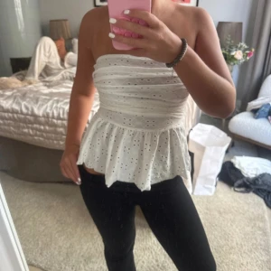 Vit topp - Superfin vit bandeau tubtopp med broderade hålmönster och volang nedtill.  Vet inte vart den är ifrån och är använd 1 gång