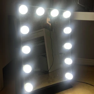 Sminkspegel med LED-belysning från Havsö - Snygg sminkspegel med 12 starka LED-lampor runt spegeln. Spegeln har touchknappar för att justera ljusstyrkan och har även tre olika färger på ljuset som går att justera. Står stadigt på en svart metallfot. Inga skador. 