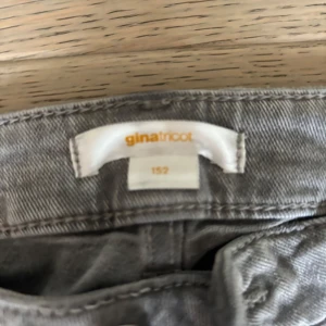 Grå bootcut jeans från Gina Tricot - Snygga grå jeans från Gina Tricot i storlek 152. Modellen har klassisk femficksdesign och bootcut-ben, vilket ger en schysst siluett. Perfekta för dig som gillar en avslappnad men trendig look.