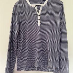 Randig långärmad tröja Scotch & Soda - Snygg långärmad tröja från Scotch & Soda i marinblått och vitt med smala ränder. Tröjan har rund halsringning, knappslå med fyra knappar och är tillverkad i 100% bomull. Perfekt för dig som gillar en avslappnad men stilren look.