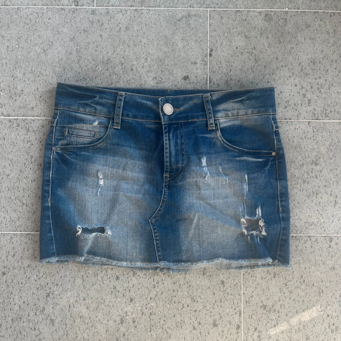 Blå jeanskjol med slitningar