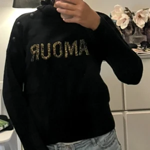 Svart stickad polotröja Zadig & Voltaire - Svart stickad polotröja från Zadig & Voltaire i storlek 12-Xs. Tröjan har höga ribbade muddar, polokrage som man kan vika ned och coolt AMOUR-tryck i guld på bröstet. Snygga knappar på axeln ger extra edge. Perfekt för dig som gillar stilrena och trendiga plagg. Pris går att diskutera. Nypris ca 1800🩷😇🌸