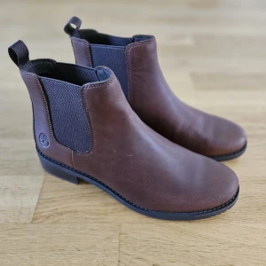 NYA! Bruna Timberland Chelsea boots, stl 39,5 - Helt nya oanvända boots från Timberland, dam stl 39,5. Sköna och superfina!   Modell Mont Chevalier mid Chelsea boots chestnut.  Gjorde ett försök att vara lite färgglad med brunt :-) men har fortsatt med svarta skor - så dessa har inte kommit till användning tyvärr.  Köpta på rea för 1 071 kr, ordinarie pris 1 599 kr. Kvitto finns.