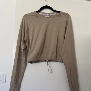 Beige långärmad tröja från ICANIWILL - Beige långärmad tröja från ICANIWILL med croppad passform och snörning i midjan. Fint skick! 