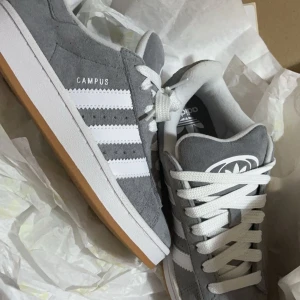 Grå Adidas Campus sneakers i mocka - Snygga Adidas Campus sneakers.Säljer ett par grå Adidas campus. Typ halvt nya köpte dom på Asos. Storlek 37!