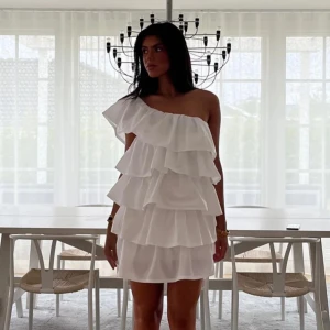 Anielle Ruffle dress vit - Säljer min klänning jag hade på studenten, då jag inte kommer få användning för den igen.  Bara använt 1 gång på dagen på studenten!  Har ingen bra bild på hur den ser ut på mig så behövde ta en bild från hemsidan!  Skulle säga att den är ganska normal i storleken, tror dock att någon som brukar ha S kan oxå ha den!  Storlek: M-tall