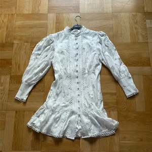 Vit spetsklänning By Emilina S - Superfin vit kortklänning från By Emilina. Passar även XS och M. Klänningen har långärmade puffärmar, knappar framtill och vackra spetsdetaljer. Perfekt till studenten och till sommaren. Använd en gång och inga defekter.