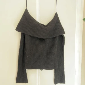 Svart offshoulder tröja - Svart stickad tröja från H&M i storlek S med offshoulder-krage och ribbad struktur. Långärmad och mjuk, perfekt för att ge en skön och snygg vibe. 