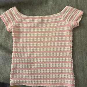 Rosa randig offshoulder topp från Nelly - Supersöt stickad topp från Nelly i rosa och vitt med randigt mönster. Toppen har korta ärmar och en offshoulder-design som ger en trendig vibe. Nästan oanvänd💕