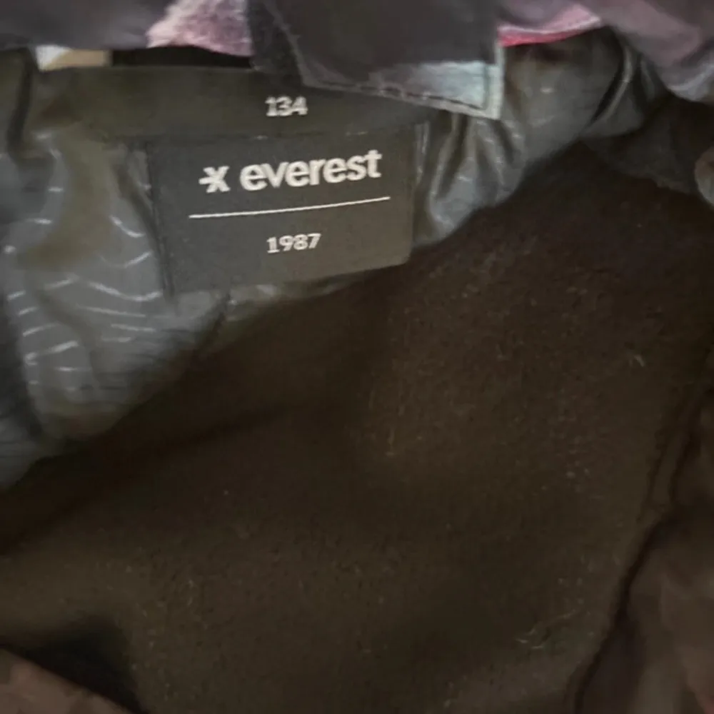 Snygga täckbyxor från Everest med ett blommigt mönster i rosa på en mörk bakgrund. Byxorna har praktiska dragkedjor och knappar framtill. Perfekta för kyliga dagar.. Farkut & Housut.