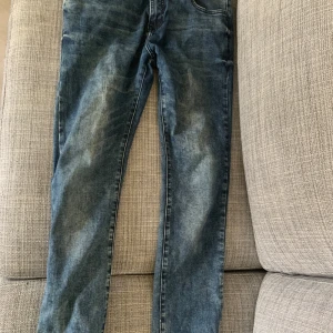 Blå jeans från Strömberg - Snygga blå jeans från Strömberg i slim fit-modell. De har en klassisk femficksdesign och en knappgylf. Perfekta för en stilren look. Även lite sköna slitningar.