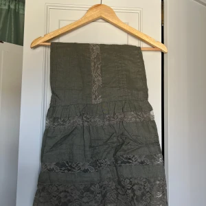 Grön midleangth kjol - En grön midleangth kjol med spets, smått utsvängd i botten. Storlek m men kan användas som en s men då som en låg midjas kjol. Jag är 170 cm och har haft den sittandes på höfterna, den har då räckt ner till ungefär mitten av smalbenen.