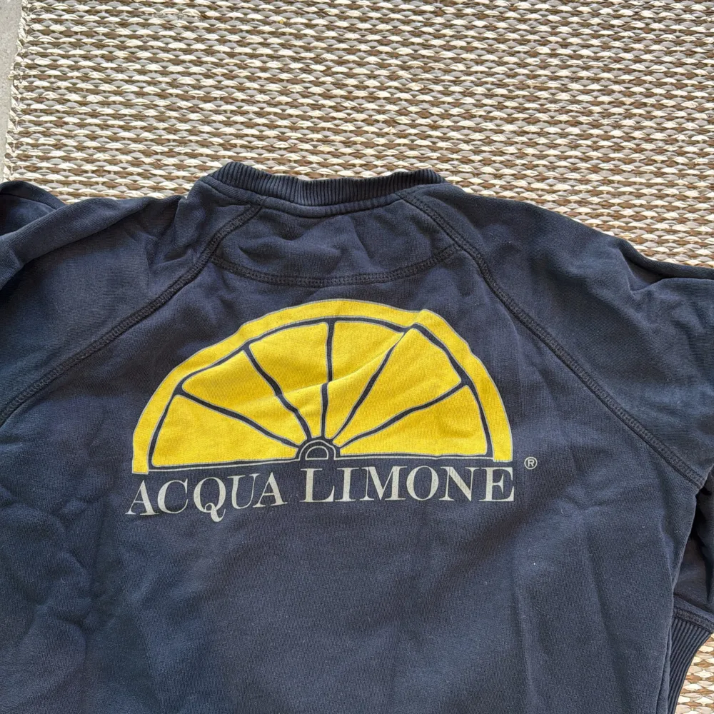 Säljer en tröja från Acqua Limone med deras klassiska logga på framsidan och en stor gul citrusdetalj på baksidan. Tröjan har långa ärmar och ribbade muddar vid ärmslut och nederkant. Perfekt för en avslappnad stil.. Neuletakit & Villapaidat.