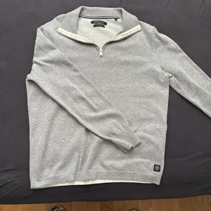 Grå cardigan i storlek S-M, perfekt inför sommaren. Grisch från Marc O'Polo - Tröjan är Storlek S, en stilren grå tröja från Marc O'Polo i 100% bomull, Tröjan har en dragkedja vid halsen och ribbade muddar vid ärmslut och nederkant. Perfekt för en laidback look.