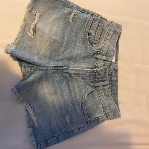Blå jeansshorts från Zara - Säljer ett par snygga blå jeansshorts från Zara. De har  slitna detaljer som ger en cool look. Perfekta för sommardagar! 