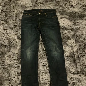 Mörkblå jeans från Polo Ralph Lauren - Snygga mörkblå jeans från Polo Ralph Lauren med klassisk femficksdesign och knappgylf. Perfekta för en stilren look.