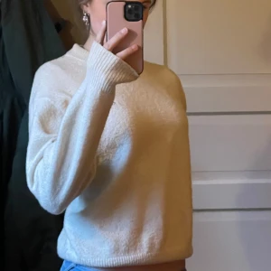 Vit stickad tröja - Säljer en mysig vit stickad tröja med rund hals och långa ärmar. Perfekt för kyliga dagar. Tröjan har en avslappnad passform och ribbade muddar vid ärmslut och nederkant. Jätte fin somrig färg också💕