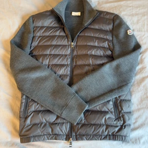 Grå jacka från Moncler - Säljer en stilren grå cardigan från Moncler med quiltad framsida och stickade ärmar. Jackan är i mycket fint skick utan några som helst skavanker. Cardiganen är i storleken M. Självklart är den äkta. Äkthetsbevis finns! Säljes eftersom att den inte kommer till användning. Köpt på wearhighend för 4500kr iår.  Hör av er vid minsta fundering😁🤝🤝