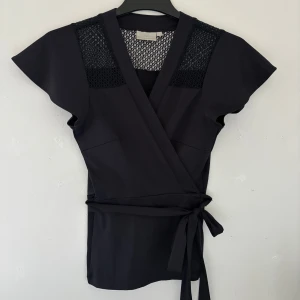 Svart lace omlottopp från InWear - Jätte fin lace wrap top från InWear, passar storlekar XS-S. Tunn material som passar till sommarn. 