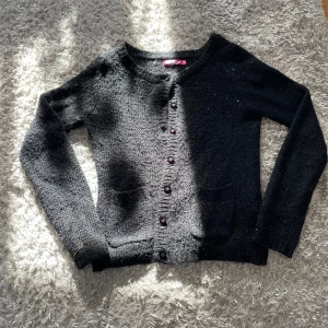 Svart kofta - Säljer en glittrig svart kofta från Indiska. Koftan har långa ärmar och knappar framtill. Storlek S