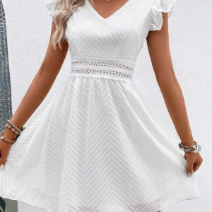 Vit klänning med spetsdetaljer - Charmig vit klänning med v-ringning och volangärmar. Den har en vacker spetsdetalj i midjan och en öppen rygg med knytning. Perfekt för sommarens festligheter!