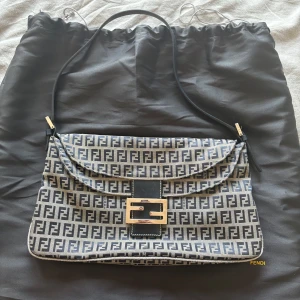 Fendi väska - Säljer min älskade Fendi väska då den ej kommer till användning. Den är i en jättefin mörkblå/grå färg! Bra skick, har försvunnit skinn på nedre delen av väskan (bild 2) va även så när jag köpte! Köpte på Collector’s Cage, sista bilden är på en likadan/liknande som de säljer nu för 7800kr💙 skriv för fler bilder osv!