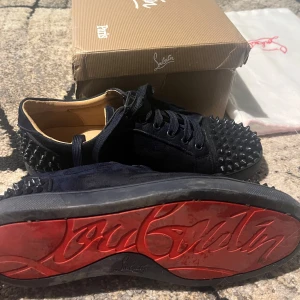 Christian Louboutin Markinblå Skor - Snygga marinblåa sneakers från Christian Louboutin med nitar på ovansidan och baksidan. Kartong, dustbag och Louboutin etikett tillkommer.