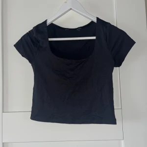 Svart croppad topp - Säljer en stilren svart croppad topp med korta ärmar. Perfekt för en avslappnad look eller att matcha med högmidjade jeans.